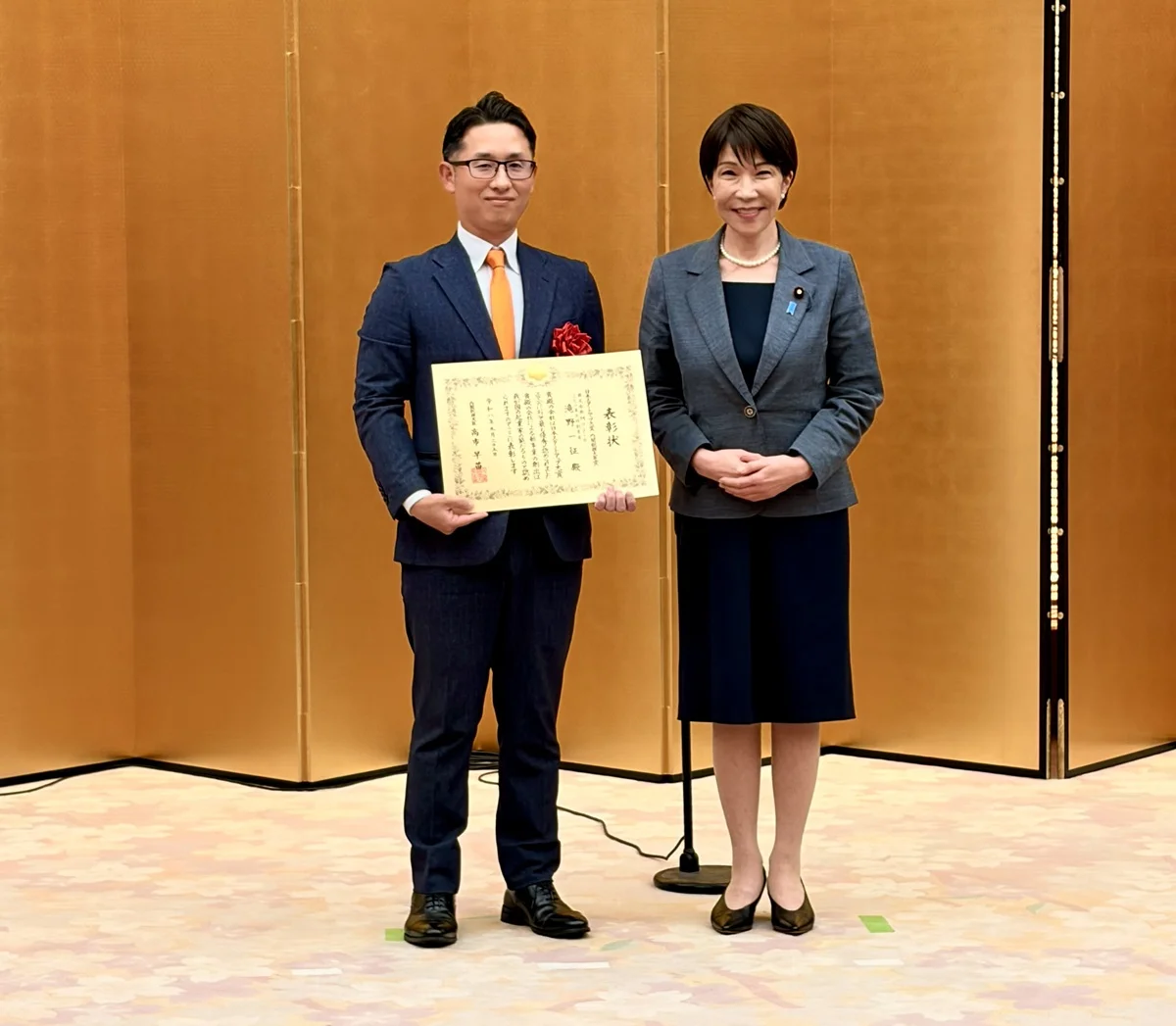 Prime Minister Sanae Takaichi presenting the award certificate to Mujin CEO Issei Takino at the Prime Minister's Official Residence